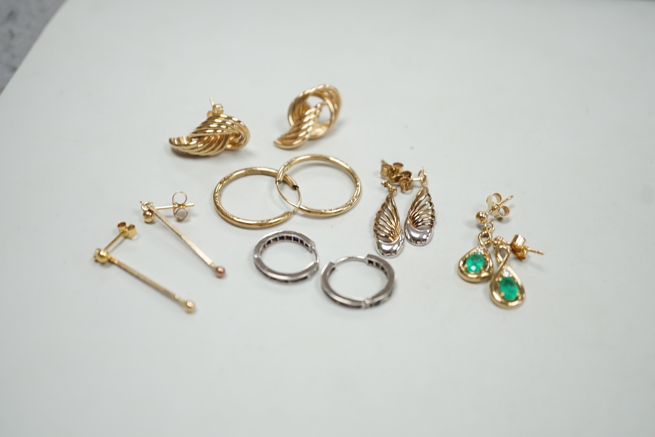 Two modern pairs of 375 earrings, a pair of 9ct, emerald and diamond set drop earrings and a pair of 9ct white gold, sapphire and diamond chip set loop earrings, gross weight 9.2 grams and two pairs of yellow metal earri